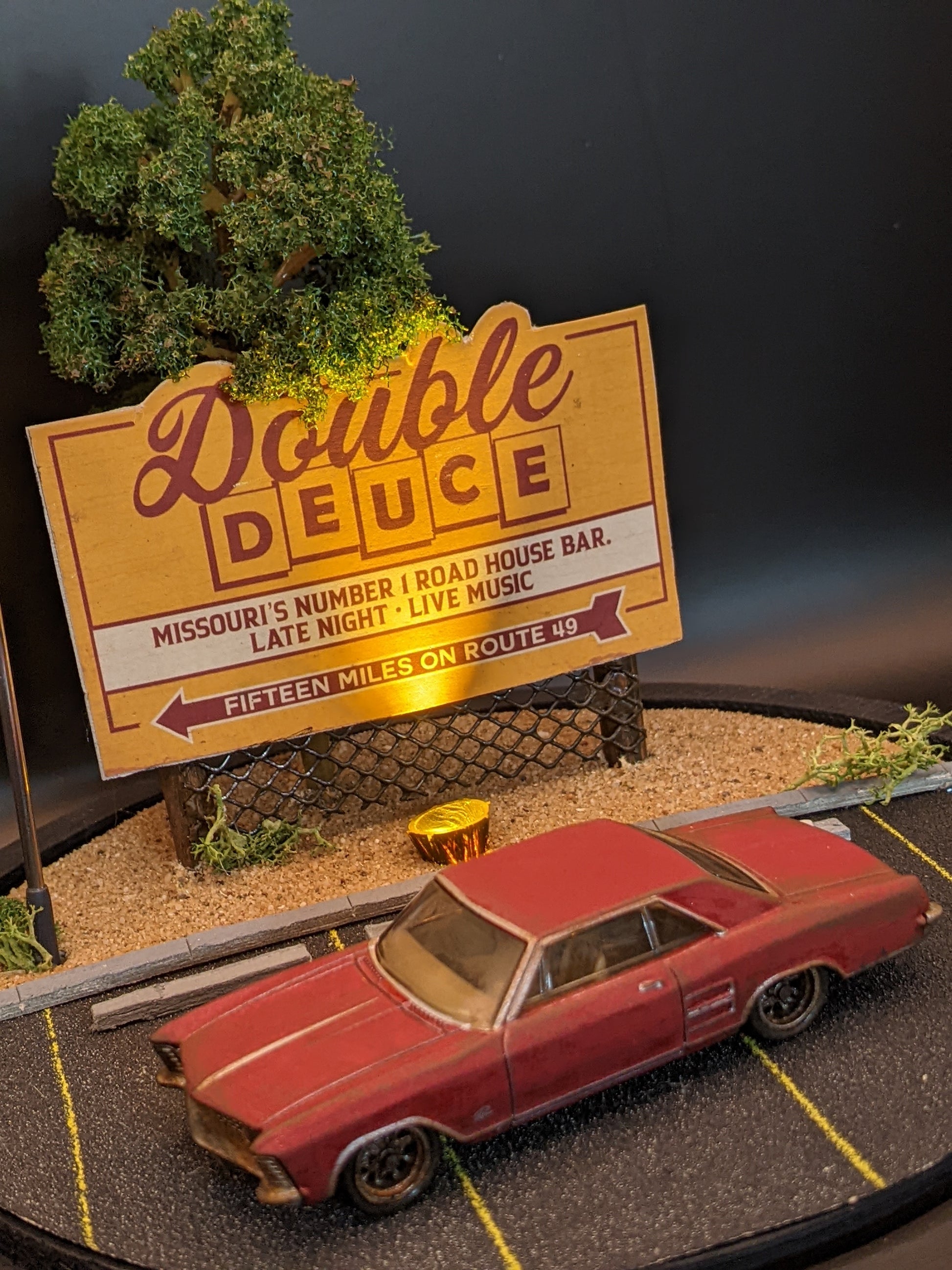 Close-up of miniature 1:64 scale car and illuminated sign inside handmade movie scene lamp.