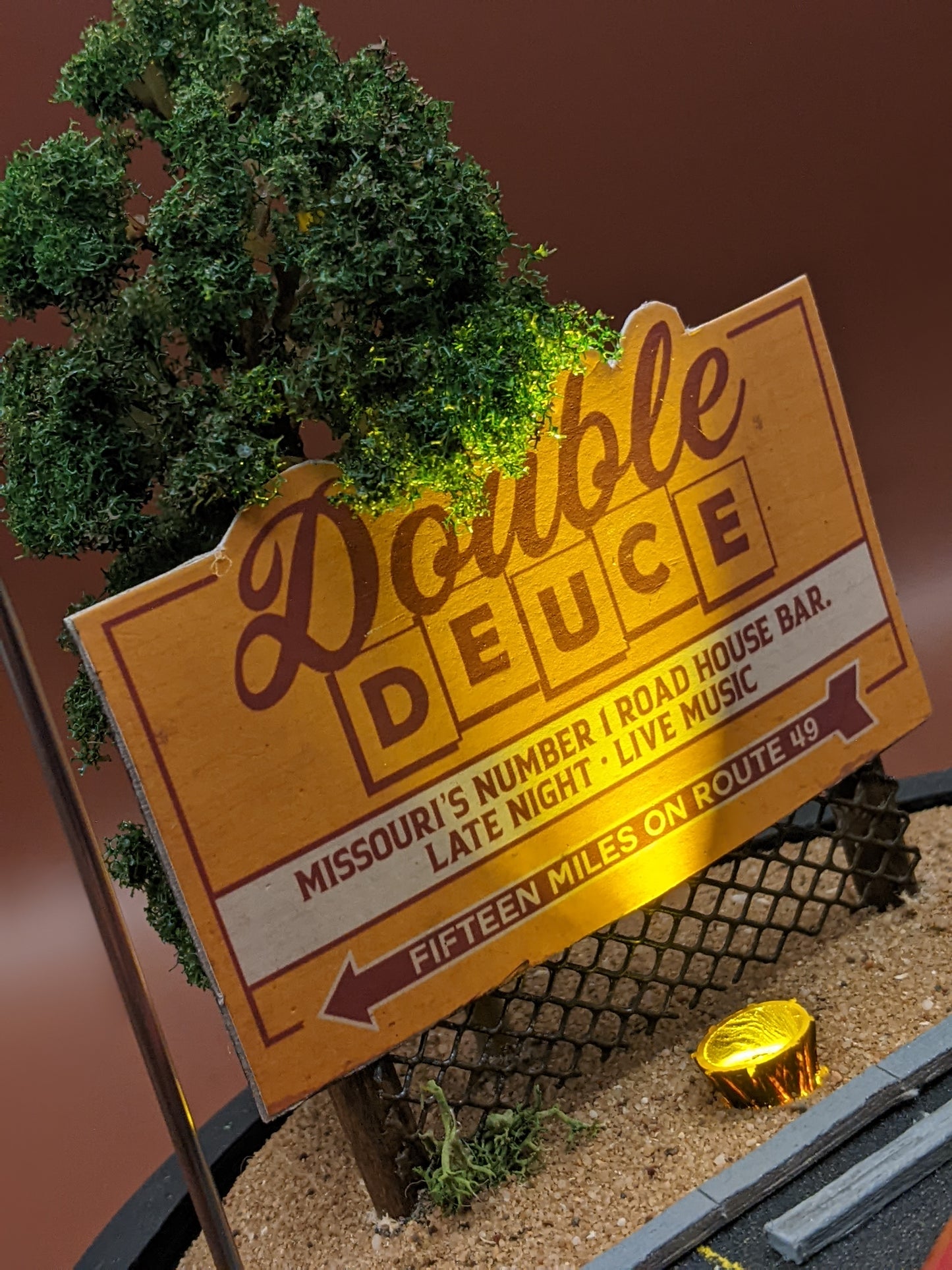 Model of a Double Deuce roadhouse sign with trees and gravel in the background