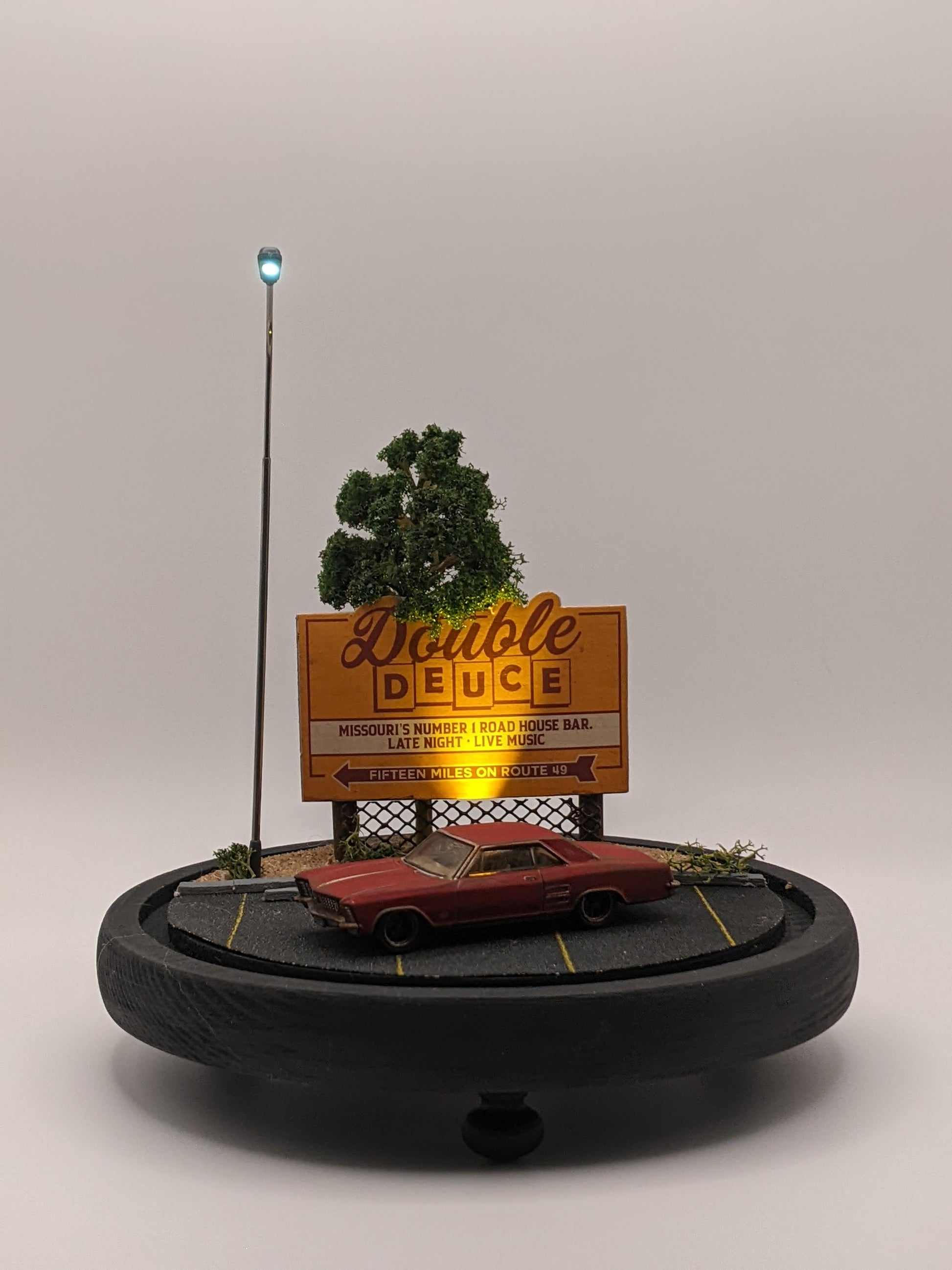 Model of a billboard with 'Double Deuce' and a car below on a gray background