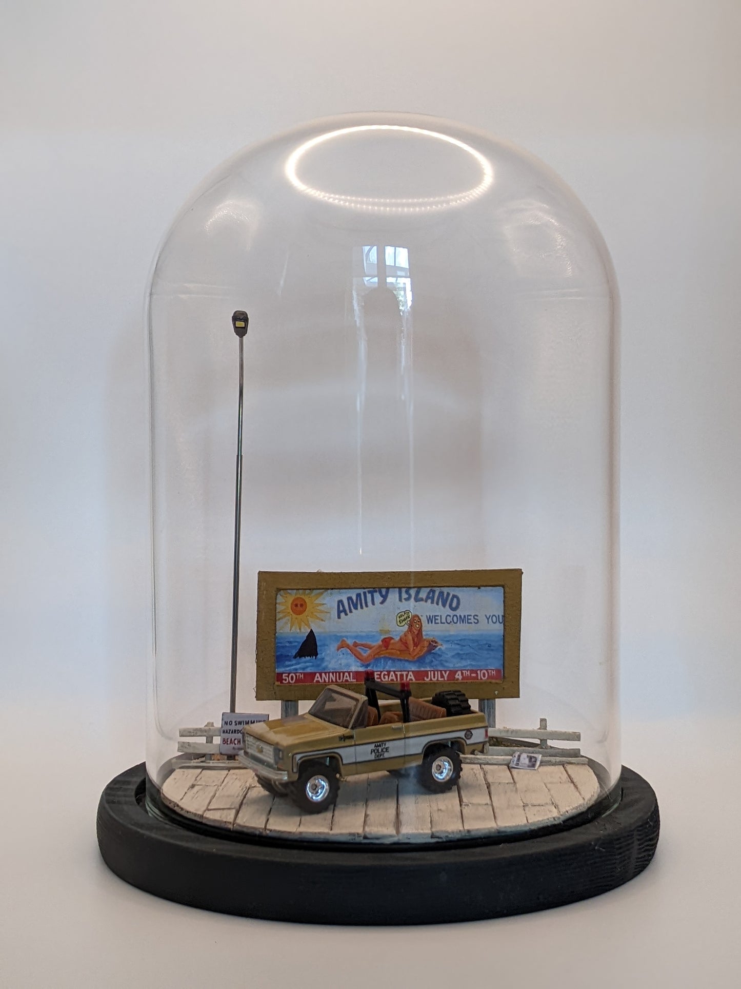 Front view of illuminated Jaws diorama lamp with warm ambient light and glass reflections.