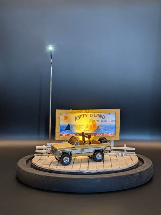 Handmade Jaws diorama lamp under glass bell jar featuring Amity Island boardwalk, sheriff’s car, and billboard.