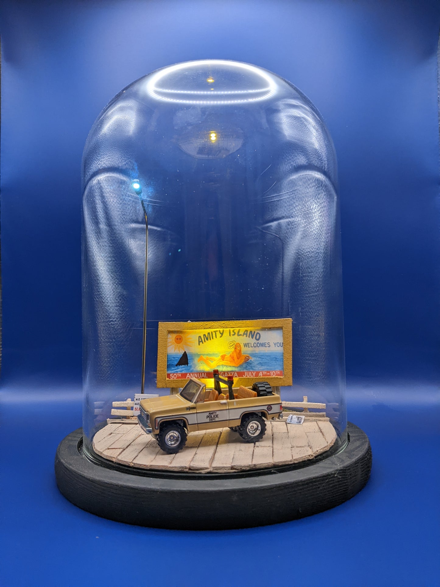 Jaws collectible bell jar lamp glowing softly, showing the Amity Island boardwalk scene at night.